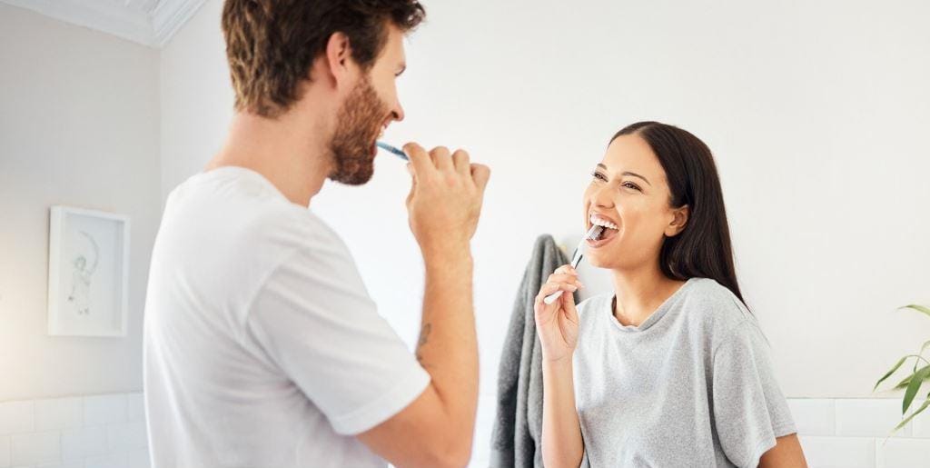 Two people brushing their teeth at home