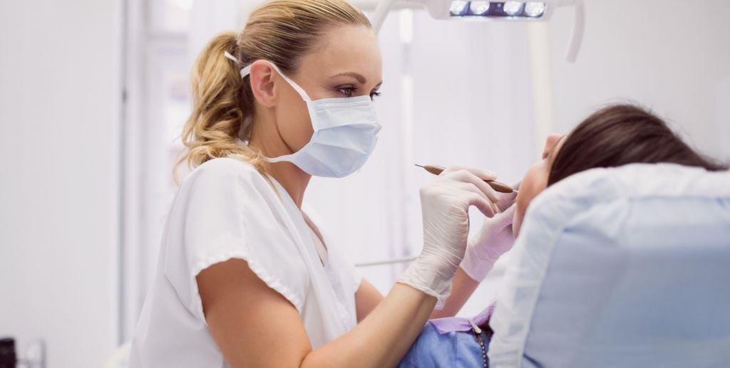 A clinician examining a patient in a dental chair