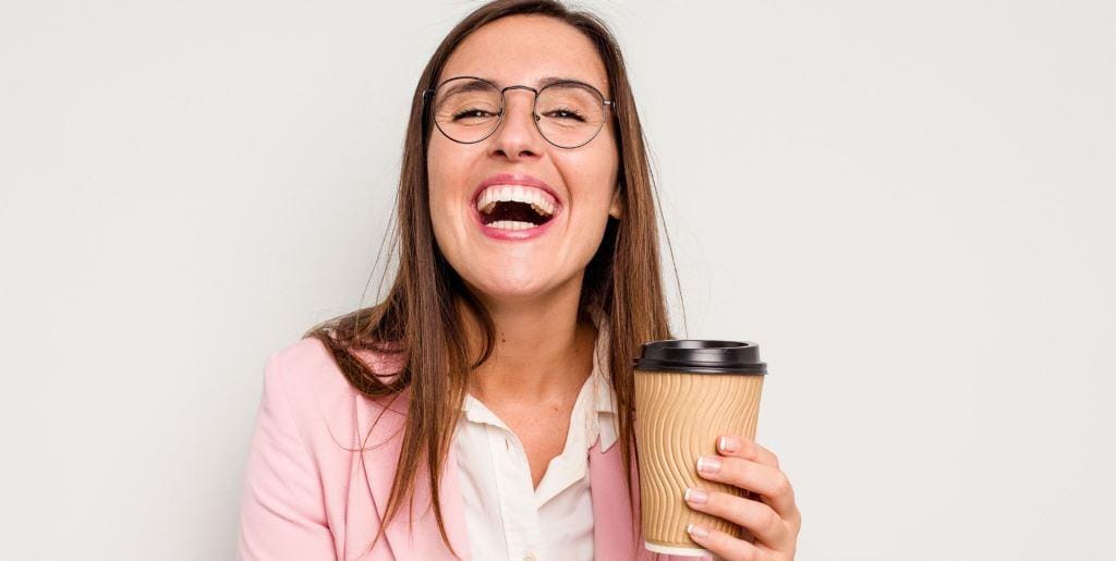 A woman wearing glasses and holding a takeaway cup