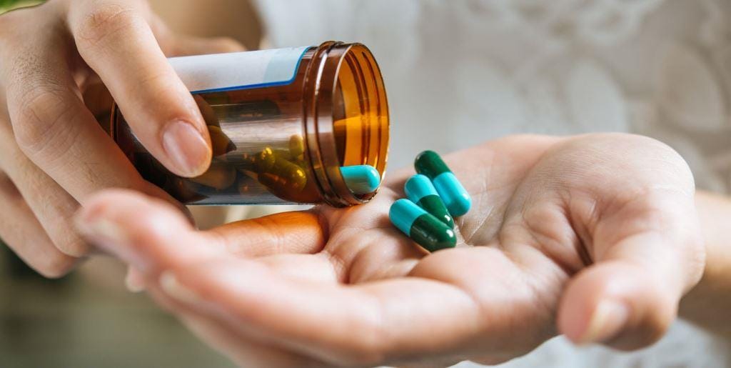 Capsules being poured from a bottle into a hand
