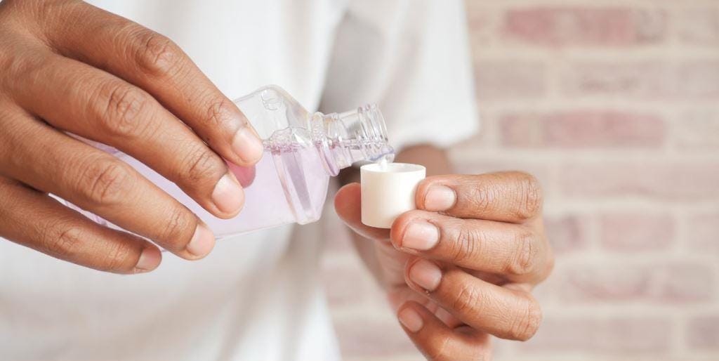 Liquid being poured from a bottle into a cap