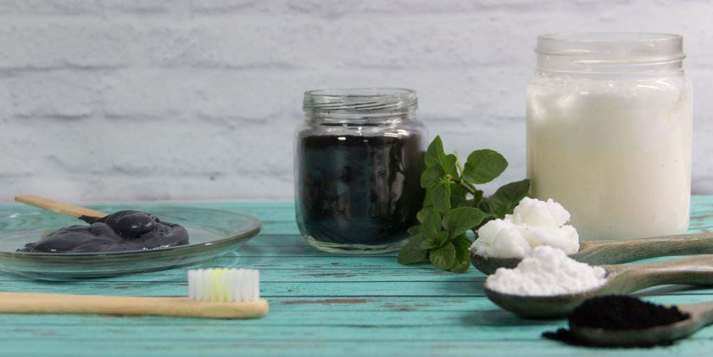 A toothbrush beside jars of dark paste and white powder