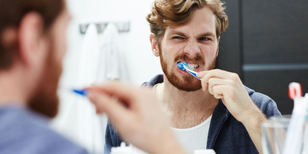 A man brushing his teeth in front of a mirror