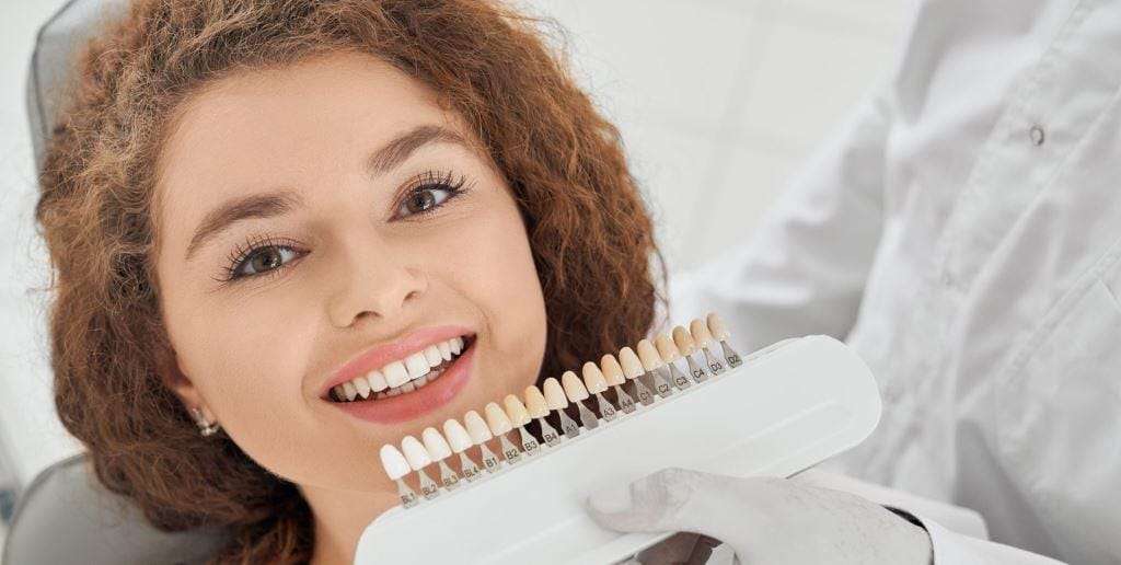 A dental shade guide held beside a smiling patient