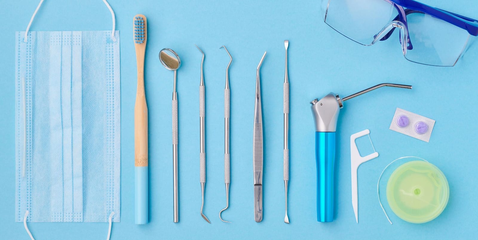 Toothbrush, floss and dental instruments on a blue surface