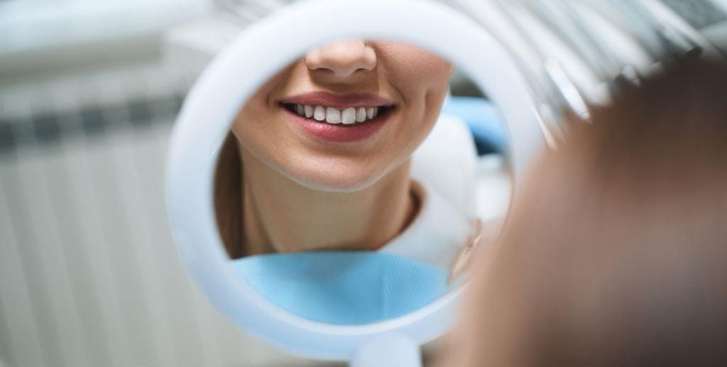 A patient looking at her smile in a hand mirror