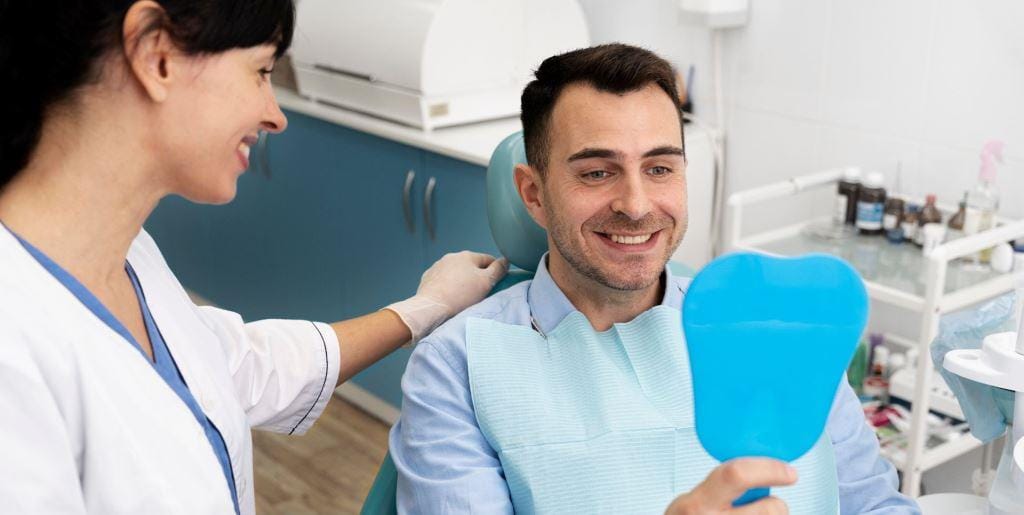 Patient holding a blue mirror beside a member of the dental team