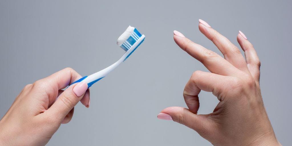 A hand holding a toothbrush beside another raised hand