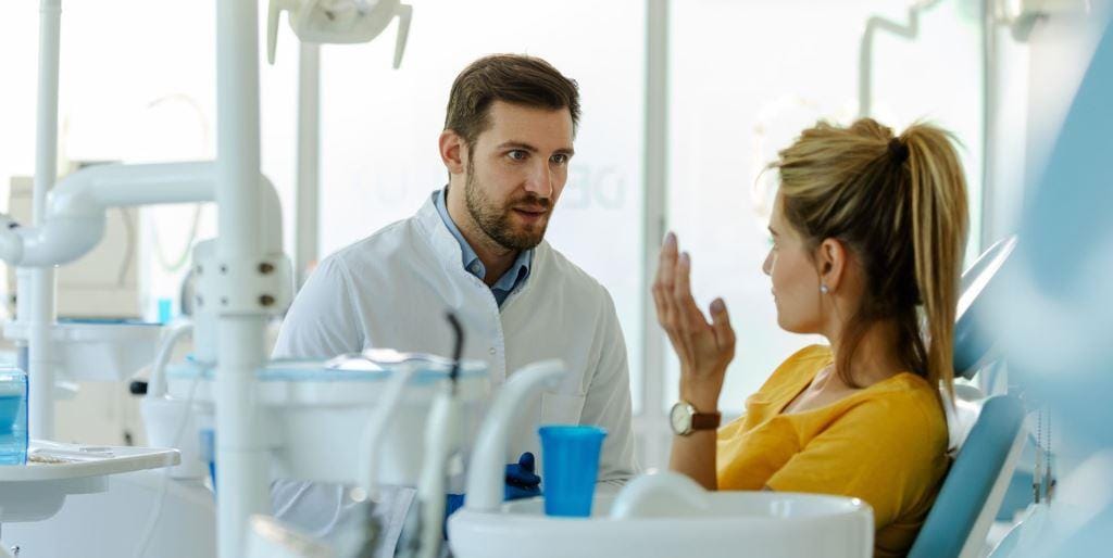 A patient talking with a dentist beside the dental chair