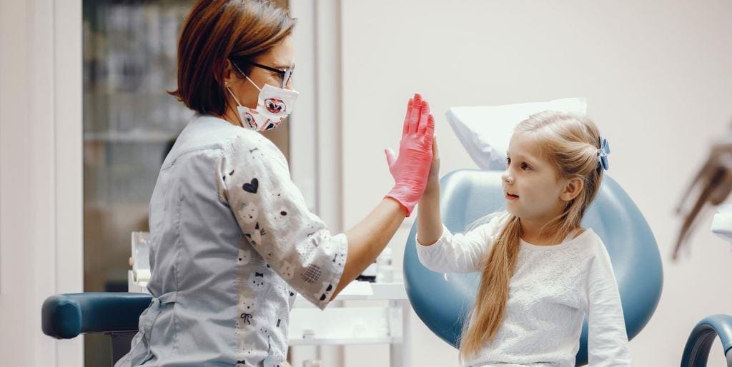 A child and a dental team member giving each other a high five