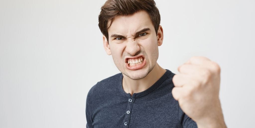 A man clenching his teeth with a raised fist