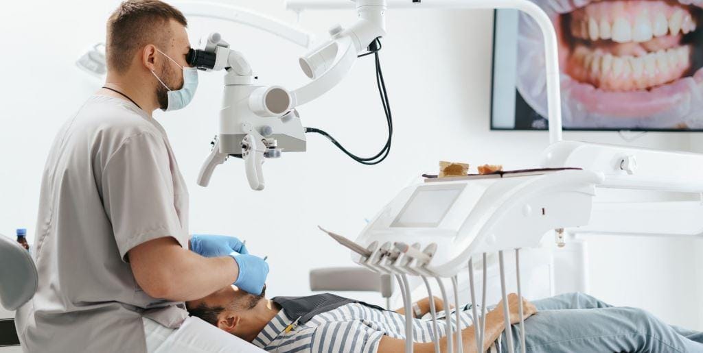 Dentist using a microscope while treating a patient