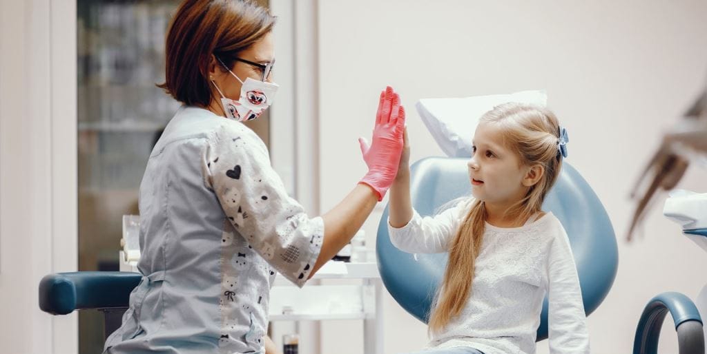 A child and dental professional giving each other a high five
