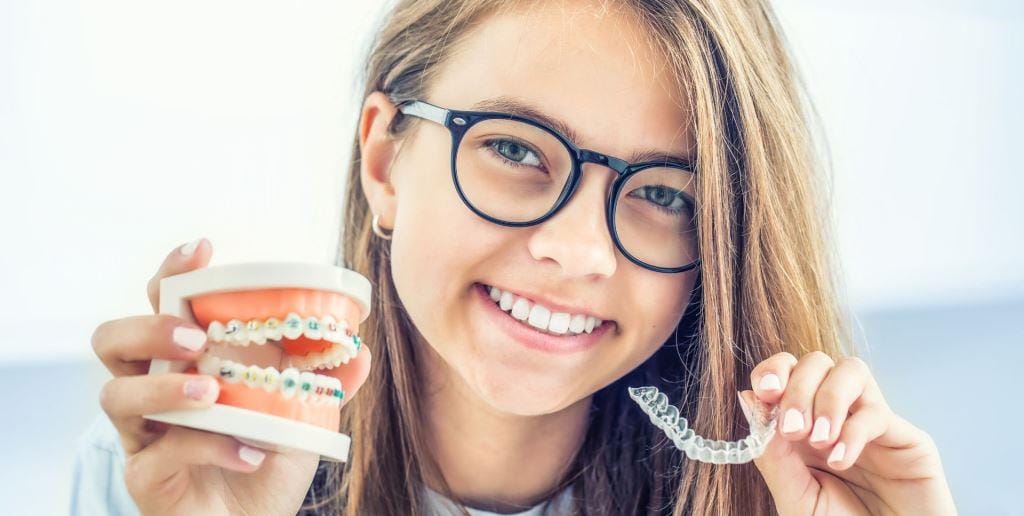 A woman holding a dental model and a clear tray