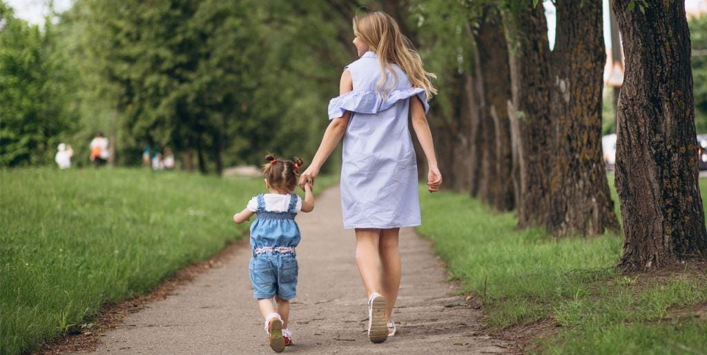 Adult and young child walking along a park path