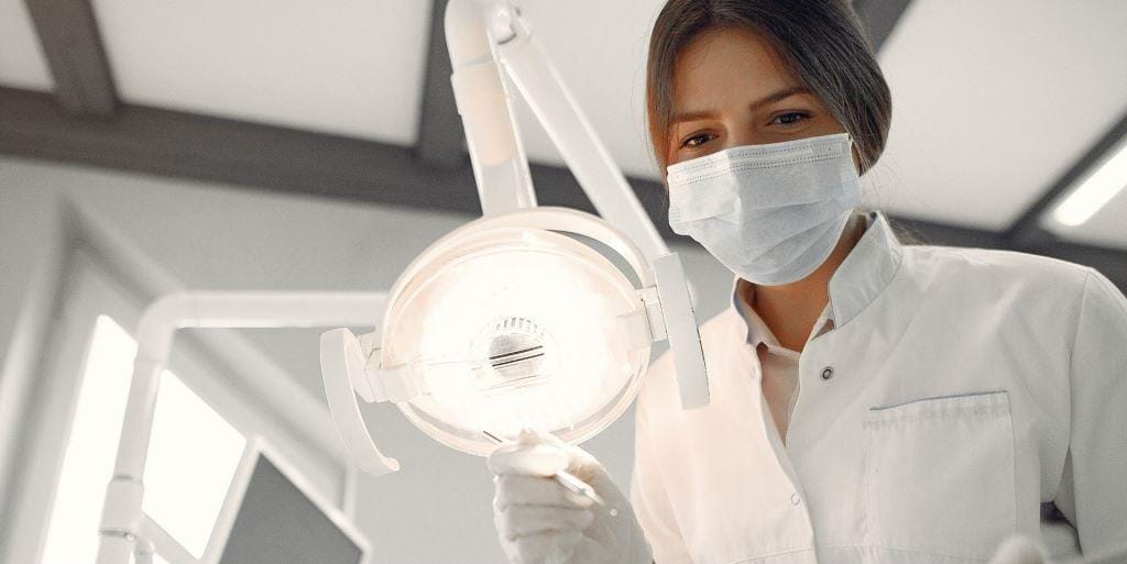 A clinician adjusting a dental lamp