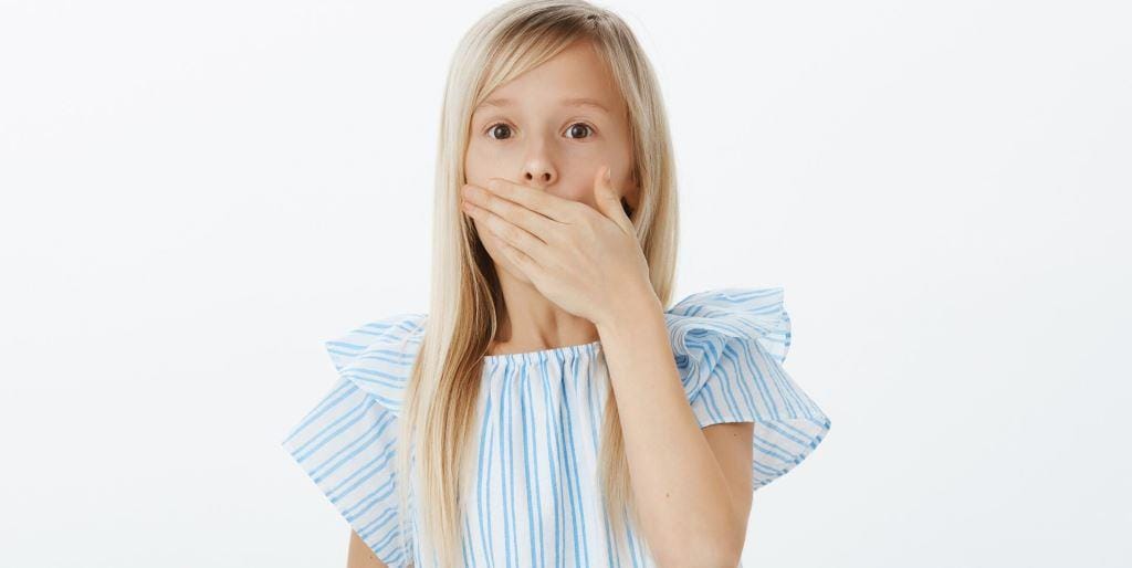 Child with a hand over her mouth