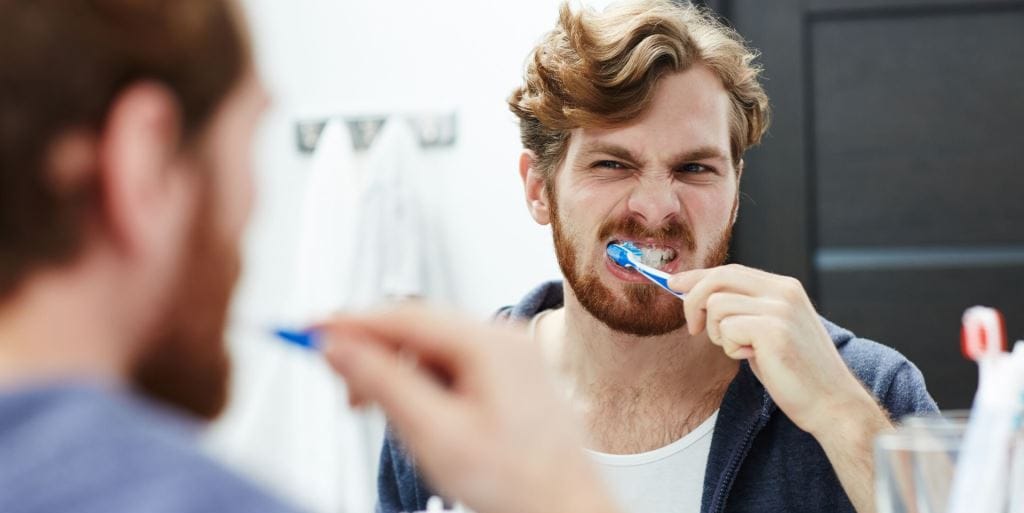 A man brushing his teeth in front of a mirror