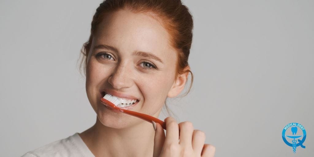 A young person holding a toothbrush against their teeth