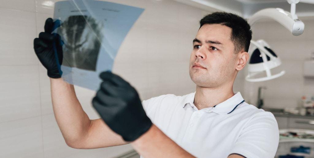 A clinician examining a dental X-ray