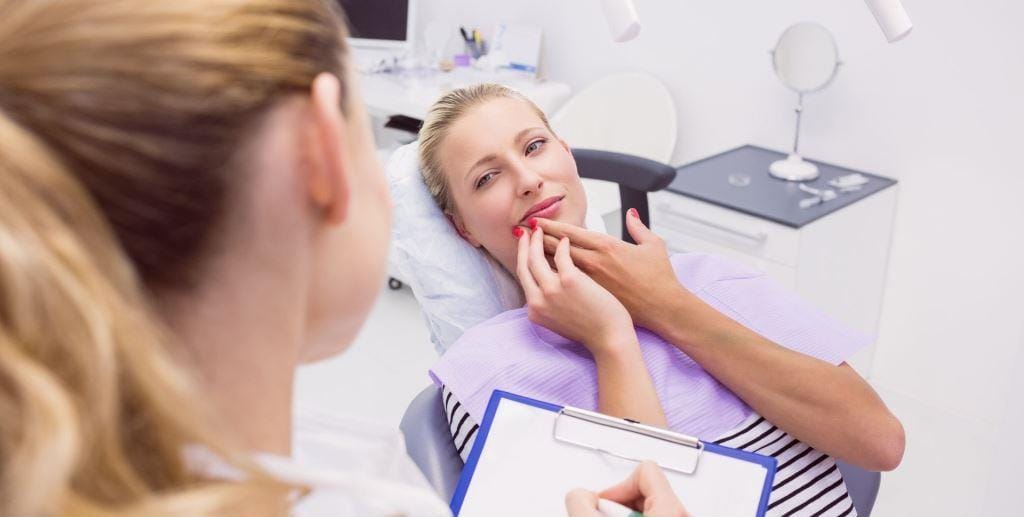 A patient indicating an area of her mouth during a consultation