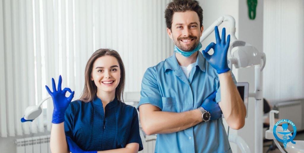 Two dental team members wearing blue uniforms and gloves