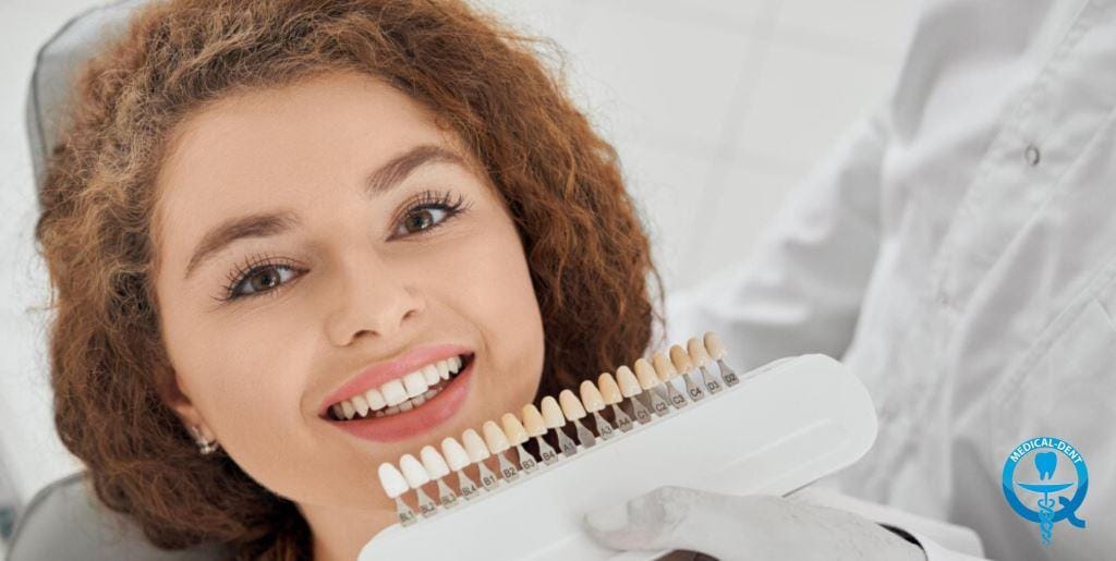 A woman holding a tooth shade guide beside her smile