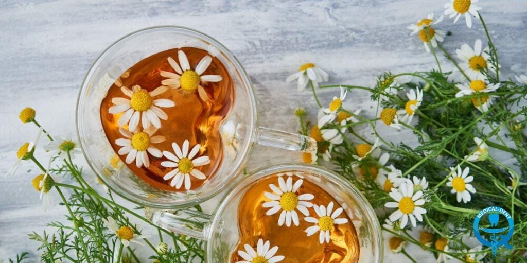 Two cups of tea beside chamomile flowers