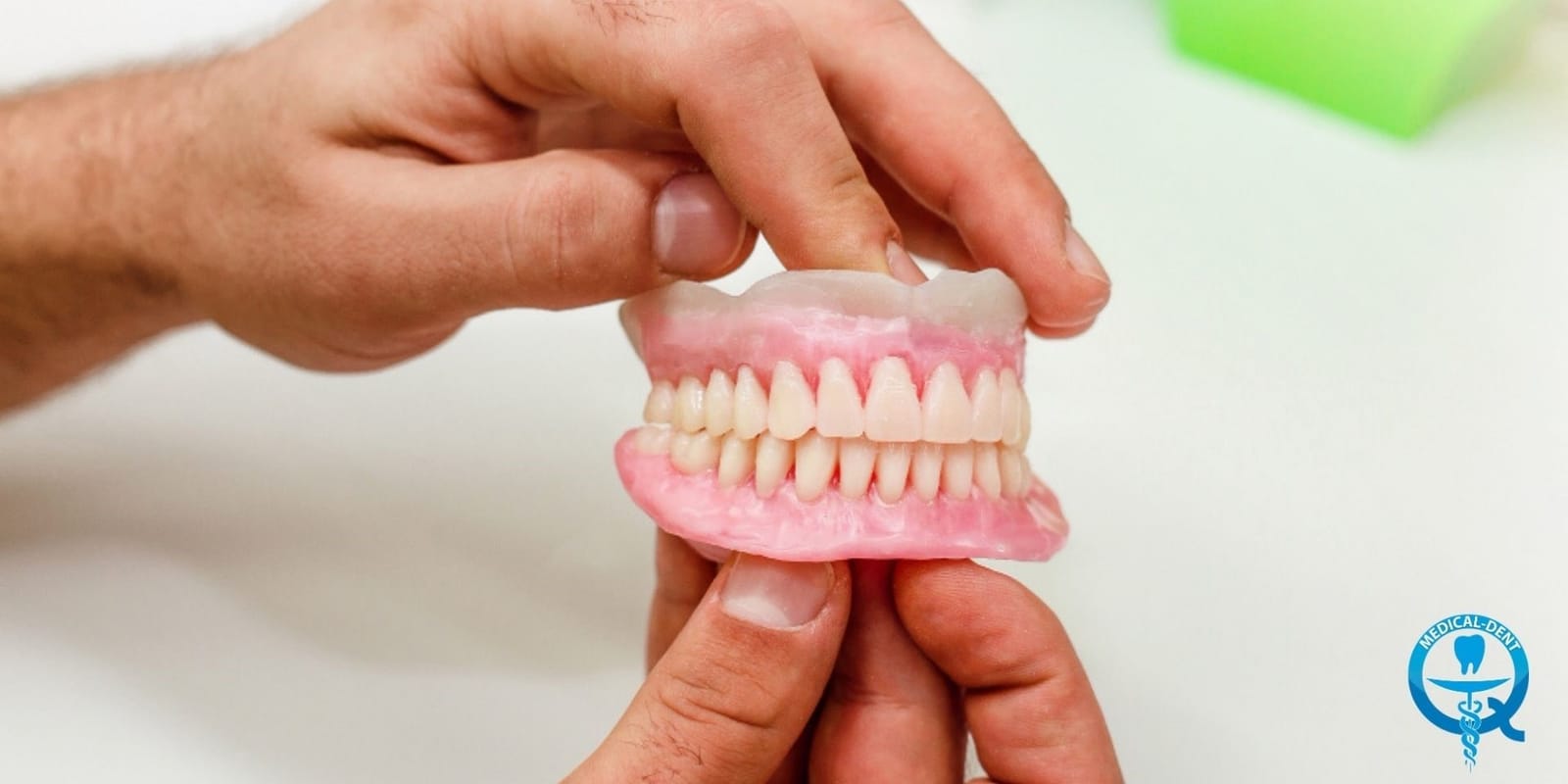 Hands holding a model of upper and lower dentures