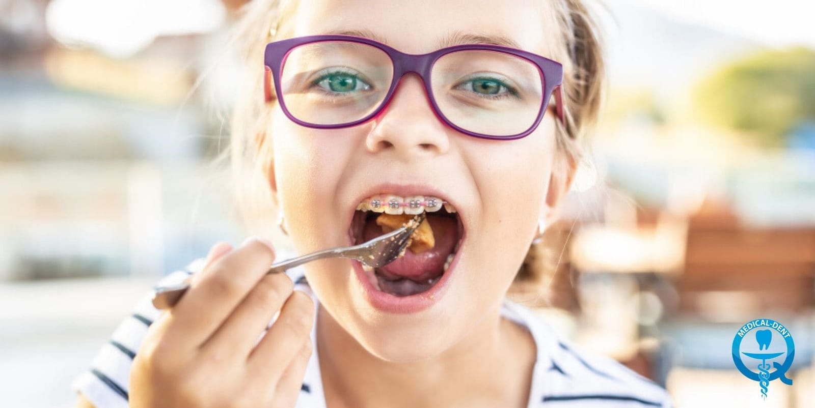 A young person wearing braces and eating from a fork