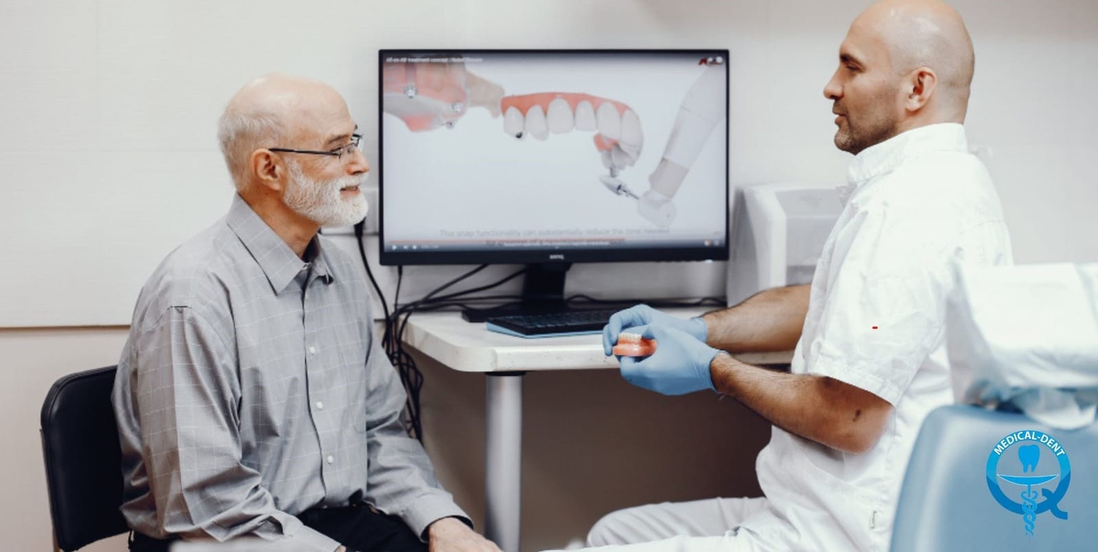 A dentist discussing images on a screen with a patient