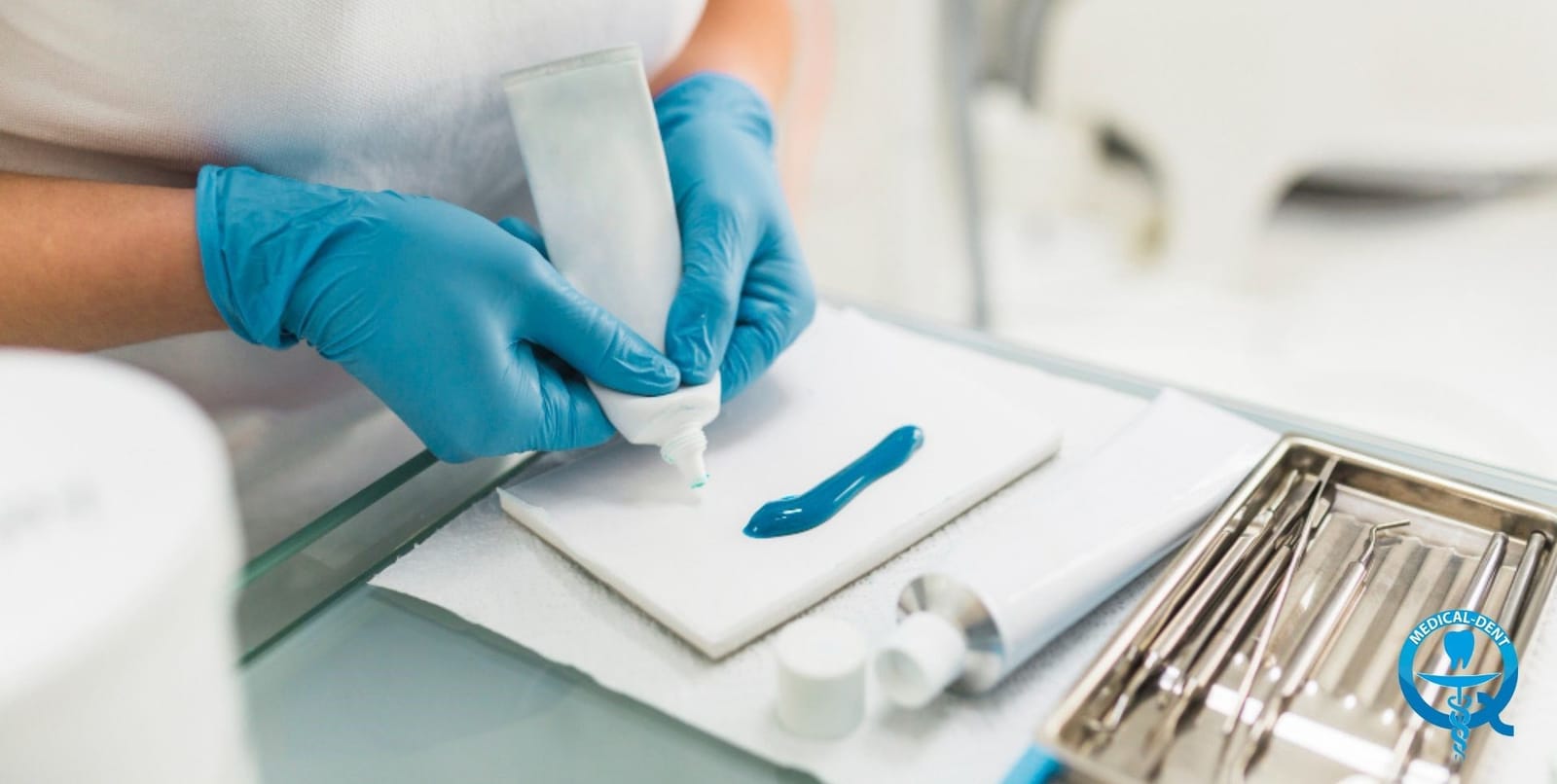Gloved hands preparing dental materials beside instruments