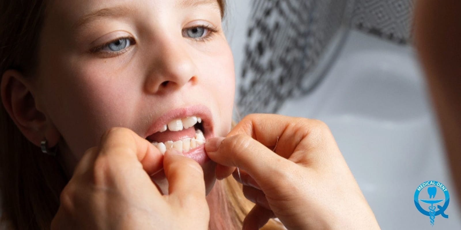 Adult helping a child clean between the lower front teeth