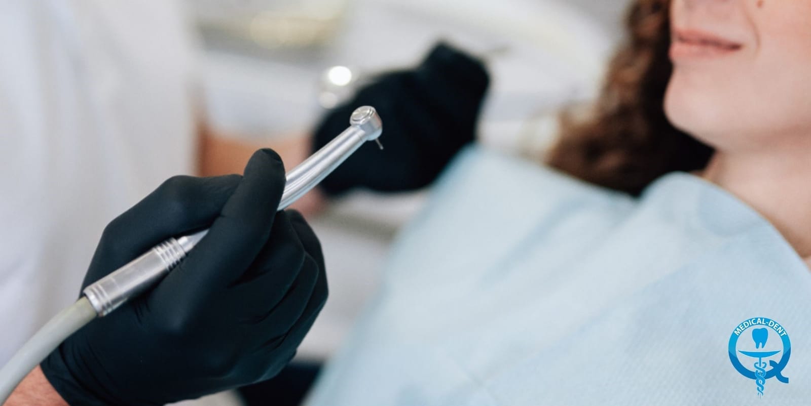 A dental handpiece held beside a patient