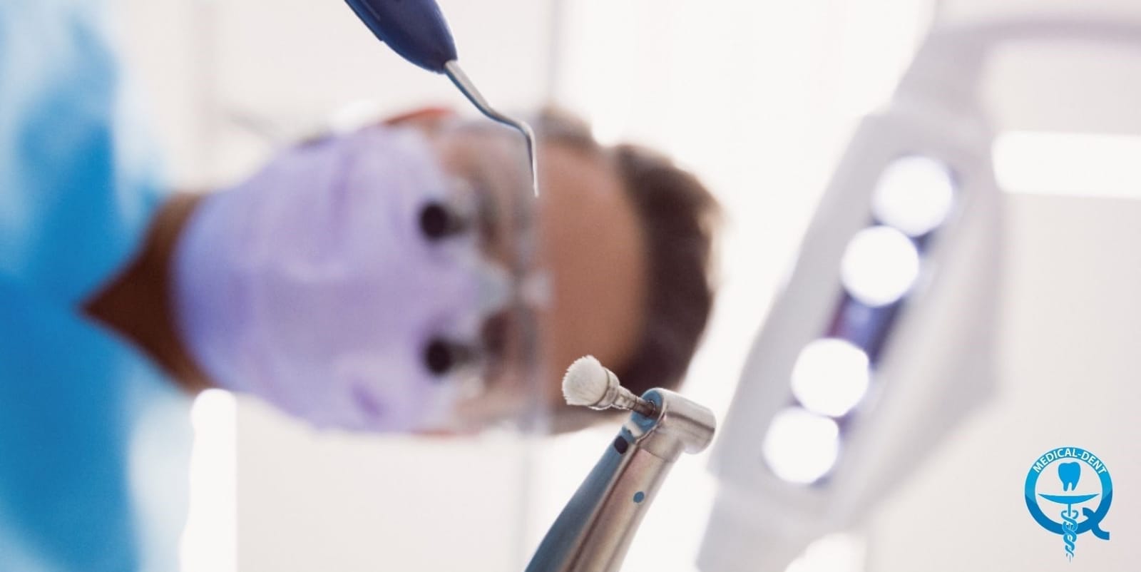 A dentist holding instruments beneath a dental light