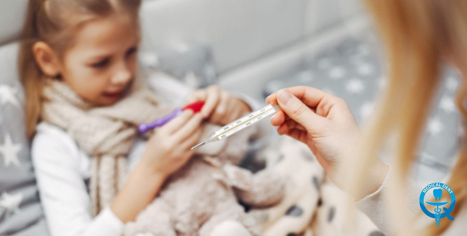 An adult holding a thermometer beside a child in bed