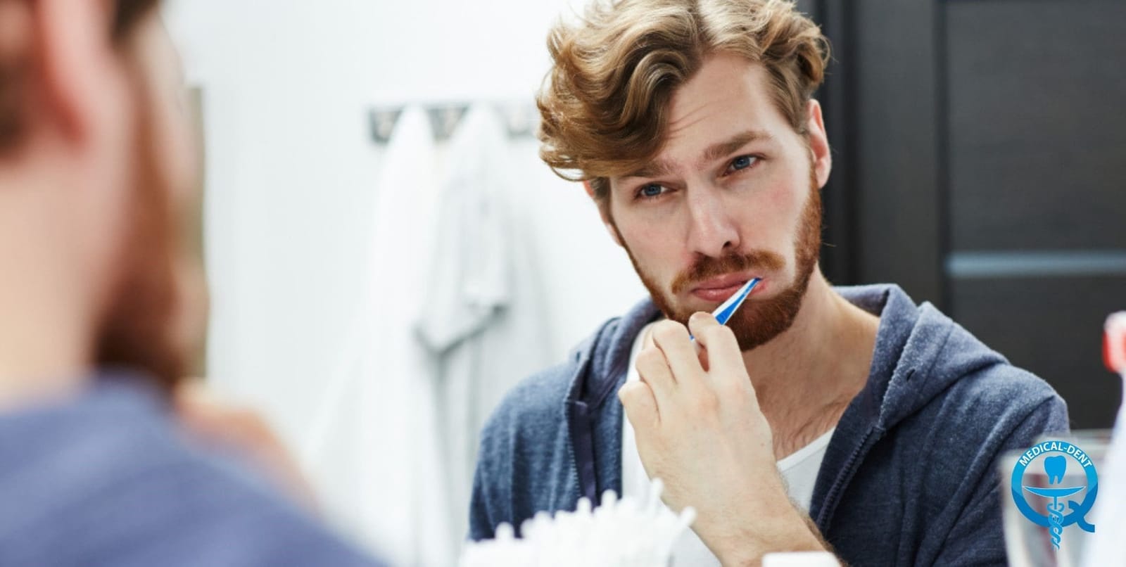 A man holding a toothbrush while looking in a bathroom mirror