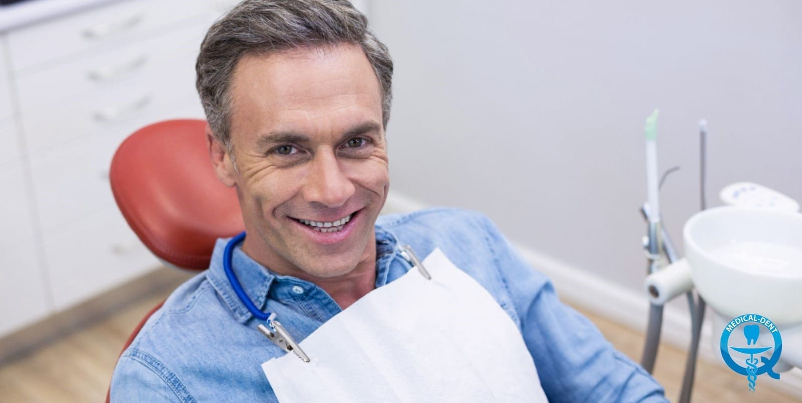 A smiling patient wearing a dental bib in a dental chair