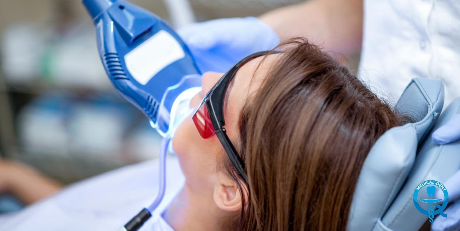 A patient wearing protective glasses beneath a whitening lamp