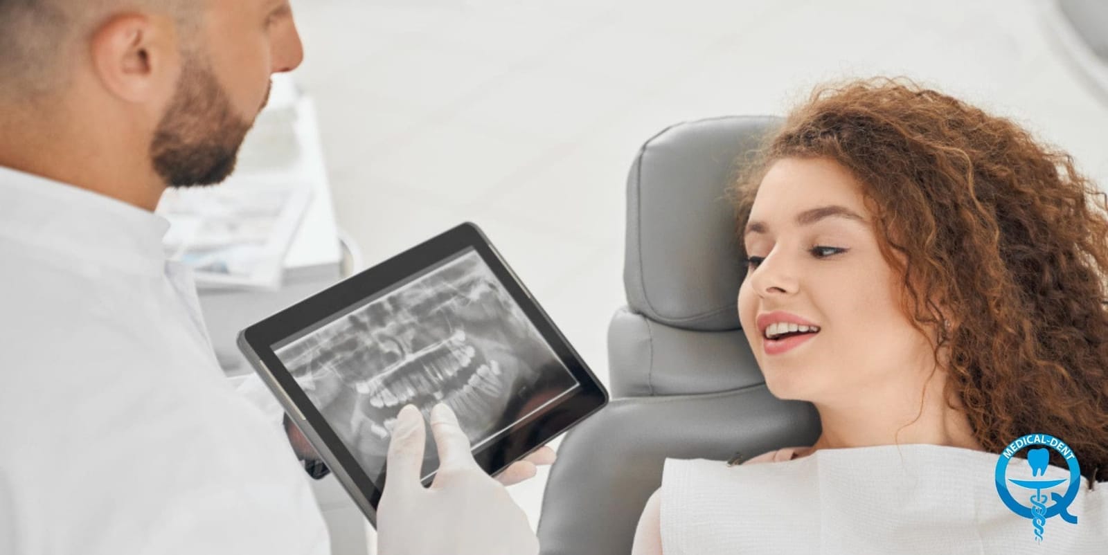 A clinician showing a patient a dental X-ray on a screen