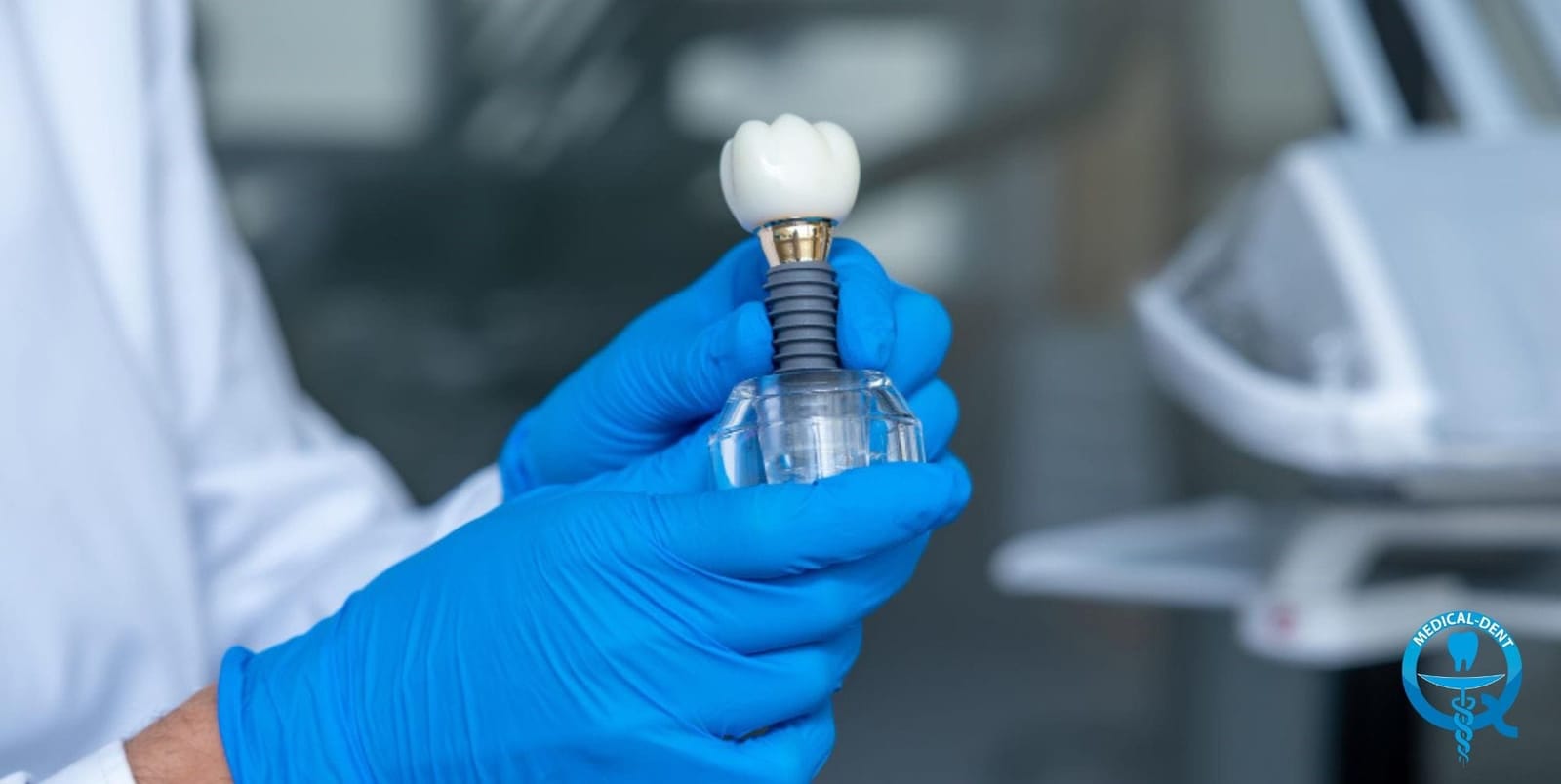 A gloved hand holding a model of an implant and crown