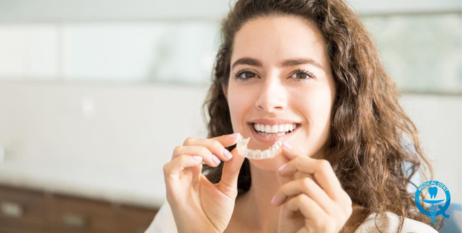 A person holding a clear dental tray near their teeth