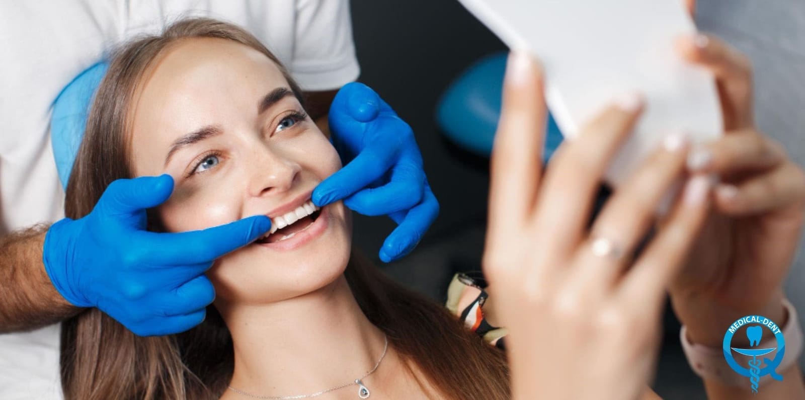 A patient looking in a mirror while a clinician checks their teeth