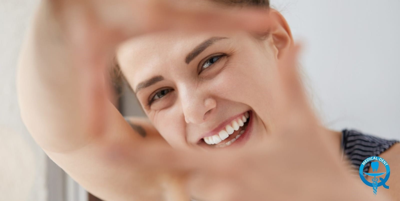 A smiling person framing their face with their hands
