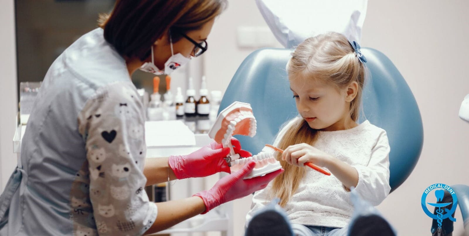 A dental professional helping a girl practise brushing on a model