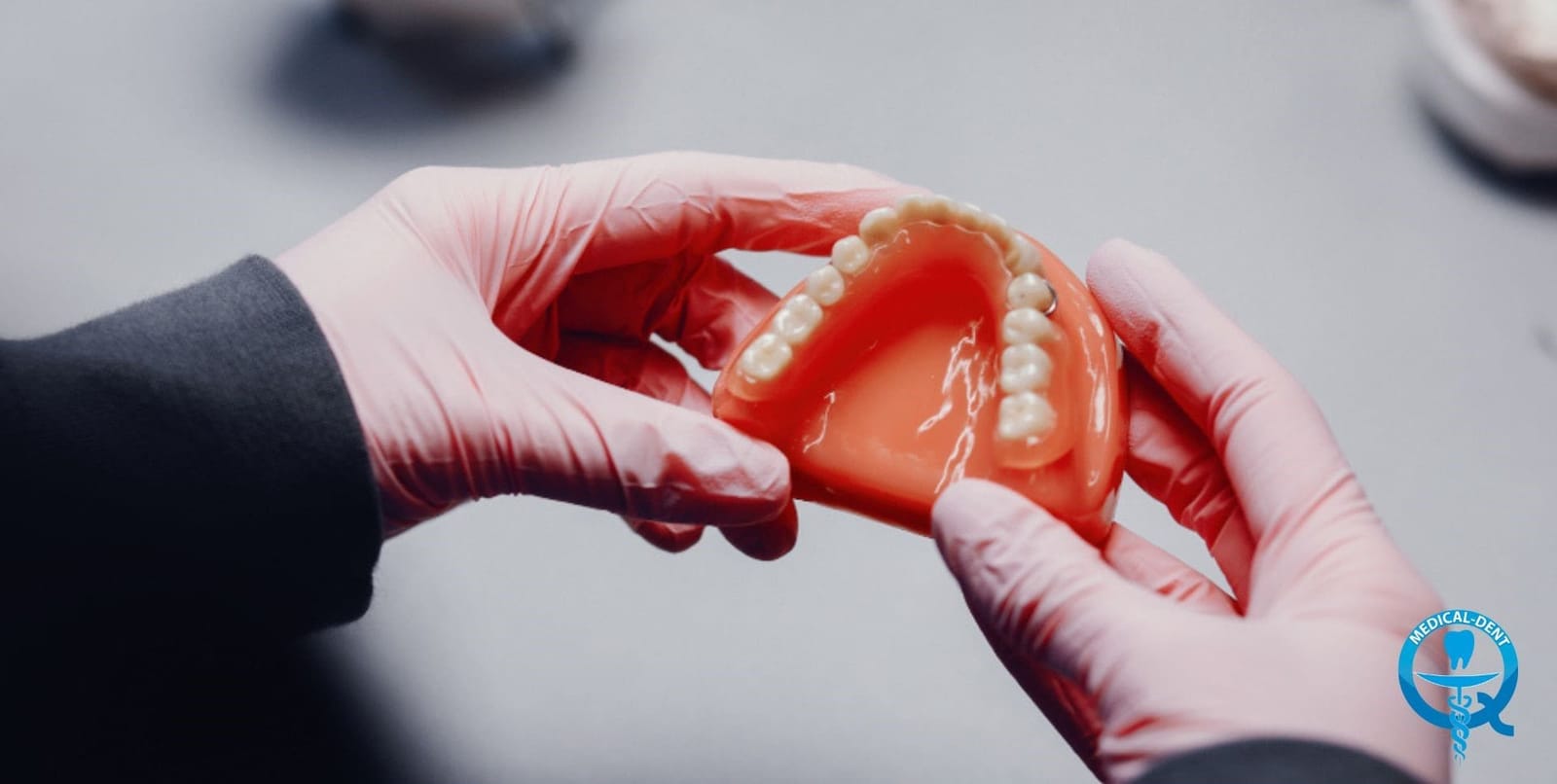 Gloved hands holding an upper denture
