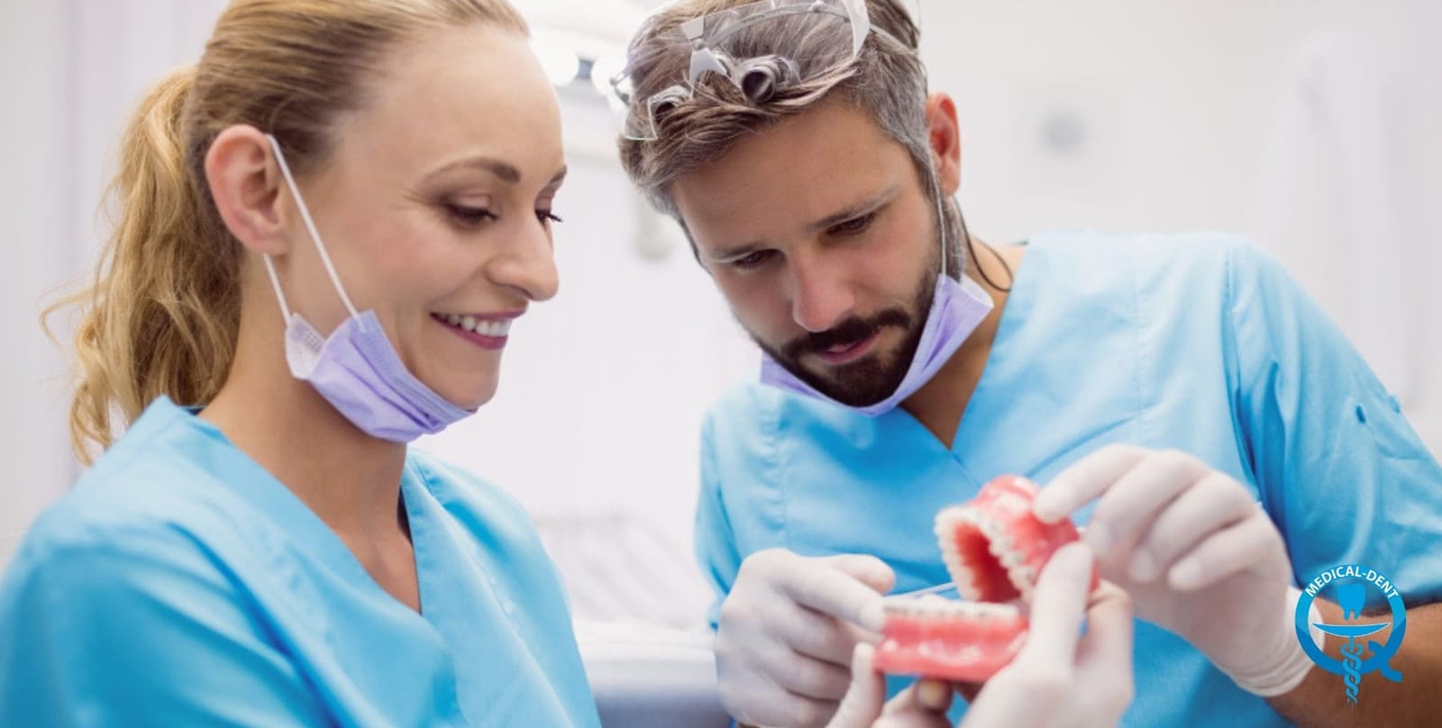 Two members of a dental team examining a model of teeth