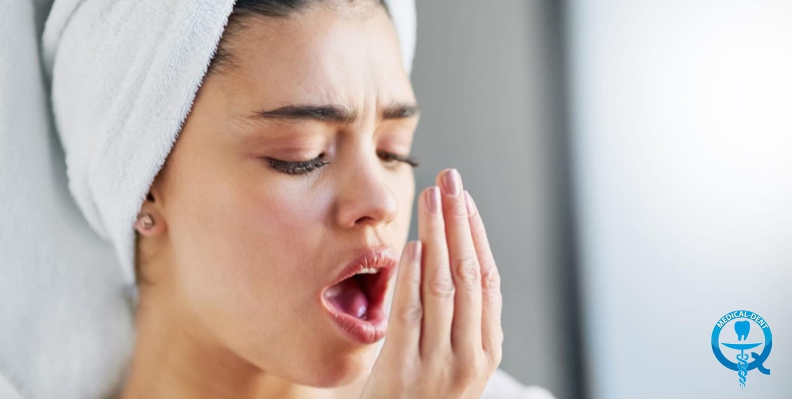 Woman holding a hand near her mouth to check her breath