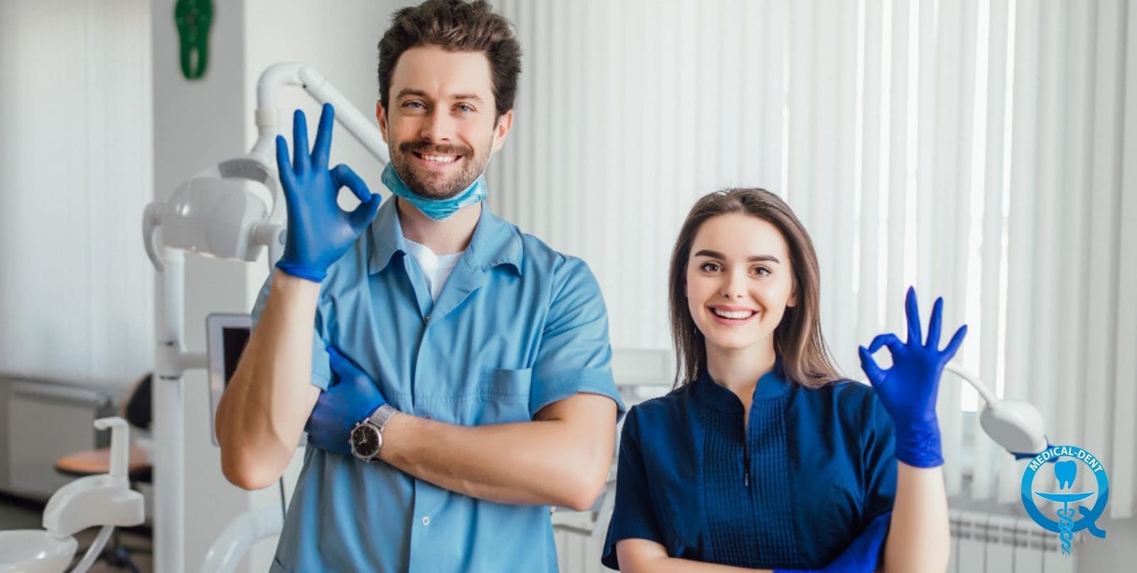 Two dental team members wearing blue uniforms and gloves