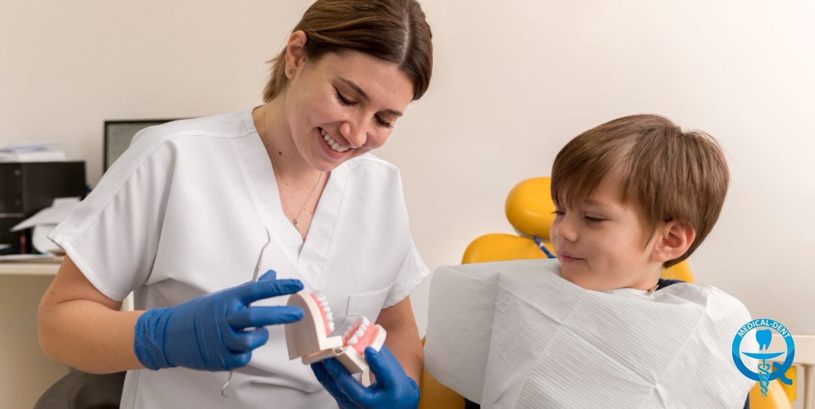 A dentist showing a model of teeth to a boy